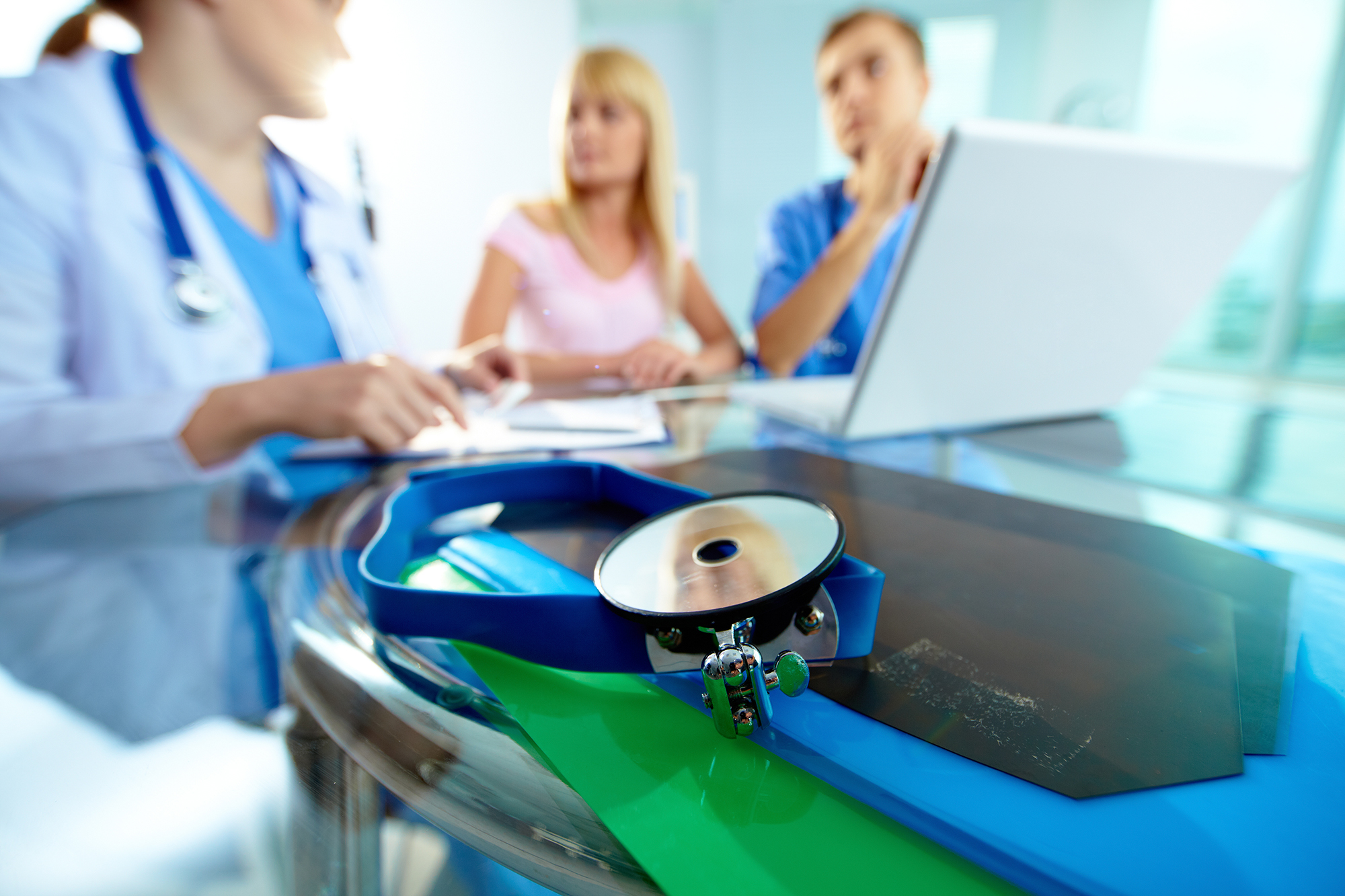 Close-up of medical equipment on background of doctors and patient working with laptop